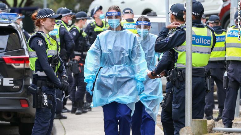 MELBOURNE, AUSTRALIA - JULY 05: Medical staff wearing PPE holding material about to walk into the Flemington Public housing flats on July 05, 2020 in Melbourne, Australia. Nine public housing estates have been placed into mandatory lockdown and two additional suburbs are under stay-at-home orders as authorities work to stop further COVID-19 outbreaks in Melbourne. The public housing towers will be in total lockdown for at least five days following a high number of positive coronavirus cases recorded in residents on those estates. The towers will be closed and contained, and the only people allowed in and out will be those providing essential services. Police will be placed on each floor of the towers and other police will control access points to the estates. Residents of 12 Melbourne hotspot postcodes are also on stay-at-home orders and are only able to leave home for exercise or work, to buy essential items including food or to access childcare and healthcare. Businesses and facilities in these lockdown areas are also restricted and cafes and restaurants can only open for takeaway and delivery.  (Photo by Asanka Ratnayake/Getty Images)